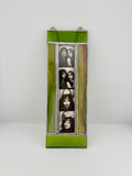 A vertical stained glass wall hanging featuring four black-and-white portrait photos of Jim Morrison and the band KISS, framed by lime green and amber-yellow panels with silver metal borders.