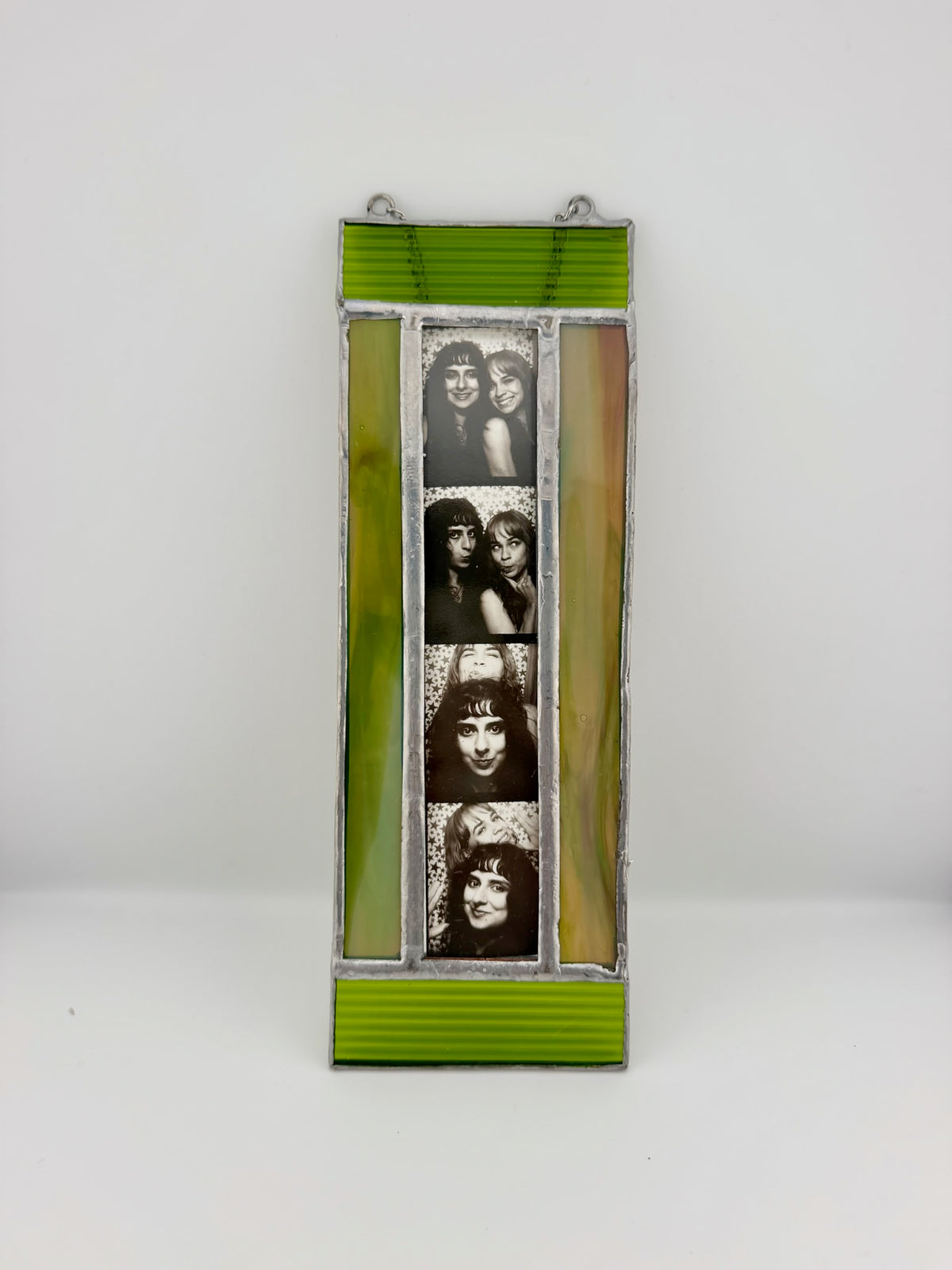 A vertical stained glass wall hanging featuring four black-and-white portrait photos of Jim Morrison and the band KISS, framed by lime green and amber-yellow panels with silver metal borders.